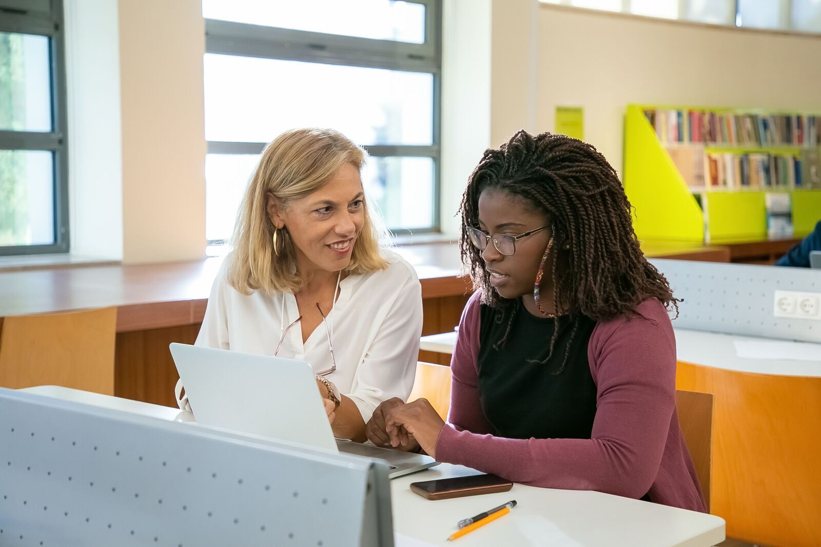 Two educators working together at a laptop