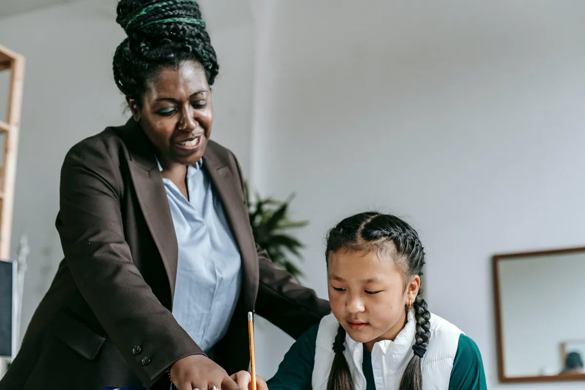 A teacher leaning in to help a student with her classwork